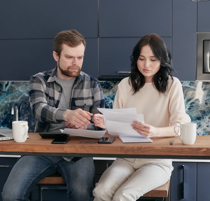 A young couple reviews bills and budget together in a modern kitchen setting.