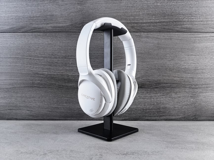 White headphones on a stand against a wooden background, showcasing modern audio equipment.