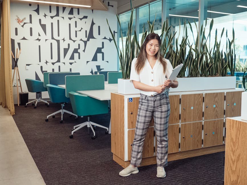 Smiling woman holding tablet in a contemporary corporate office setting.